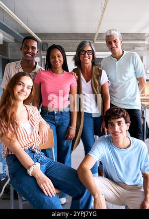 Portrait of happy multiracial group of student posing together in class with grey-haired teacher. Stock Photo