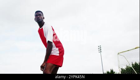 Football player striking a ball in the field on a sunny day Stock Photo