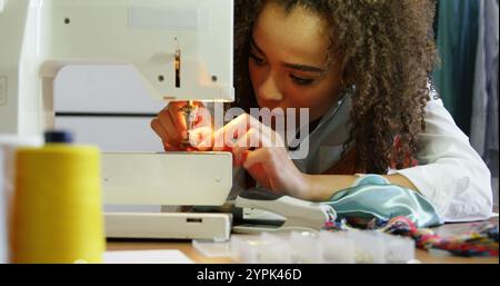 Female fashion designer working with sewing machine in workshop Stock Photo