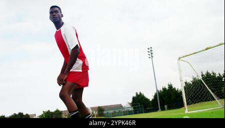 Football player striking a ball in the field on a sunny day Stock Photo