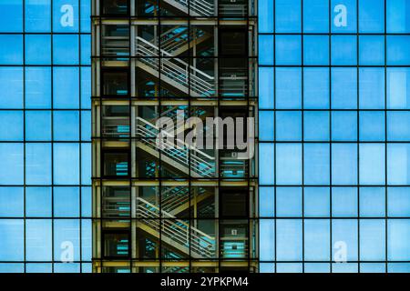 Modern Glass Facade Showcasing Internal Staircases with Symmetrical Patterns and Reflections Stock Photo