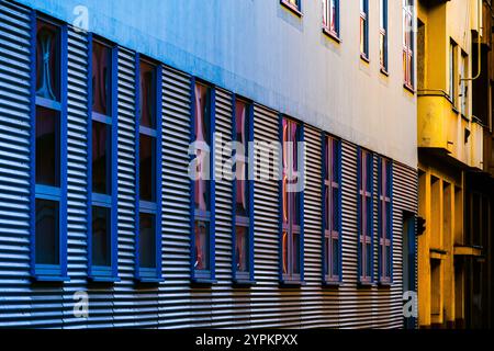 Vibrant Urban Facade with Corrugated Metal Panels, Colorful Reflections, and Modern Window Design Stock Photo