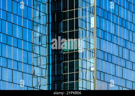 Modern Glass Facade with Symmetrical Patterns and Reflections under the blue sky Stock Photo