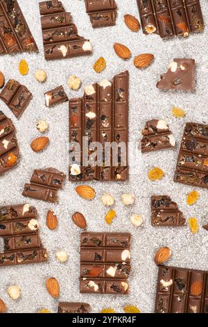 Broken chocolate pieces with nuts and raisins on a stone background top view Stock Photo
