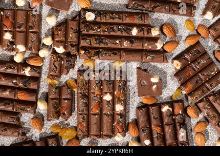 Broken chocolate pieces with nuts and raisins on a stone background top view Stock Photo