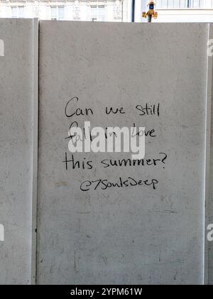 Handwritten Urban Wall Message Asking "Can We Still Fall in Love This Summer?" in a Cityscape Setting Stock Photo