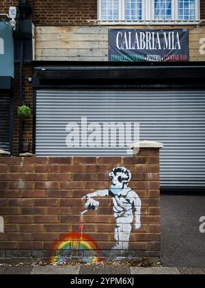 Street mural of a child painting a rainbow on a brick wall outside a shuttered Italian restaurant in urban setting Stock Photo