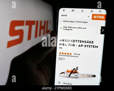 In this photo illustration, a person is holding a cellphone with the webpage of German power equipment company Stihl Holding AG Co. KG with logo. Stock Photo