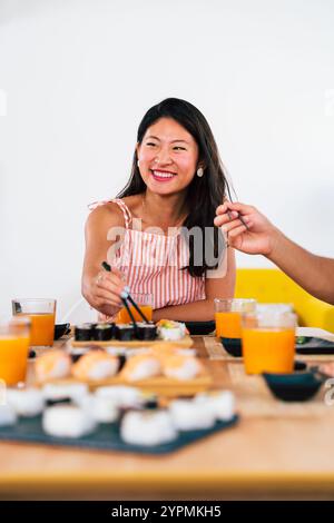 Multiethnic group of young friends meeting at home and eating sushi - Multiracial happy people bonding while having lunch Stock Photo