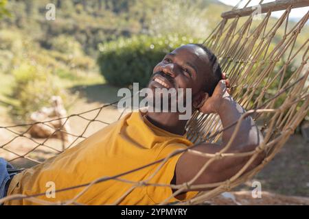 African American man enjoying nature, resting on a hammock during summer vacation in a glamping resort in Europe. Stock Photo