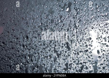 A window with raindrops on it. The drops are small and scattered. The window is clear and the rain is falling Stock Photo