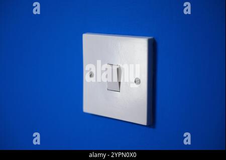 White light switch on a vibrant blue wall Stock Photo