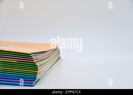 A stack of books with different colored covers. The books are piled on top of each other. The top book is orange Stock Photo