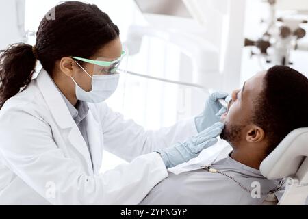 Portrait Of Black Male Patient Getting Teeth Treatment With Dentist At Clinic Stock Photo