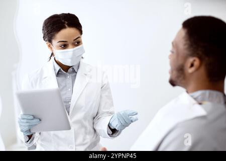 Stomatologist Woman With Digital Tablet In Hands Consulting Male Patient Stock Photo