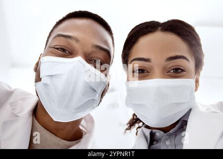Portrait Of Two Happy Black Medical Workers In Protective Masks Taking Selfie Stock Photo