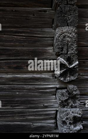 a close-up view of weathered, textured wooden logs forming the corner of a traditional log structure. The dark, aged wood showcases deep grain pattern Stock Photo