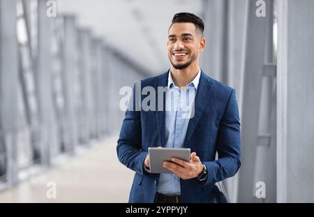 Portrait Of Happy Arab Man With Digital Tablet Standing At Airport Terminal Stock Photo