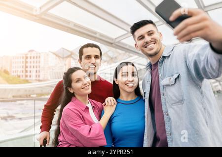 Young couple enjoys vacation at airport while taking a selfie with friends Stock Photo
