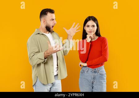 Couple having a heated discussion against a bright yellow background Stock Photo