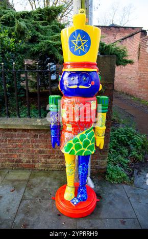 Colorful and whimsical statue of a nutcracker soldier with vibrant patterns stands on a sidewalk in front of a brick wall outdoors York UK Stock Photo