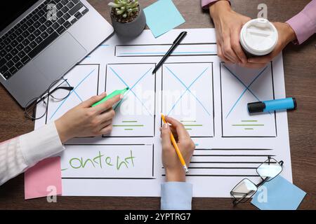 Developing UI design. Designers creating website wireframe on paper at wooden table, top view Stock Photo