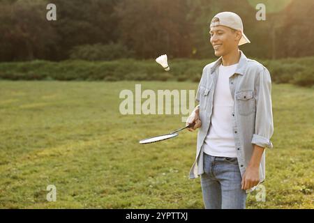 Young man playing badminton racket in park on sunny day Stock Photo