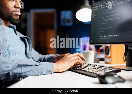 Network administrator functioning via computer programming at home, entering script code for safety and confidentiality. On terminal window, african american technician diagnoses system. Stock Photo