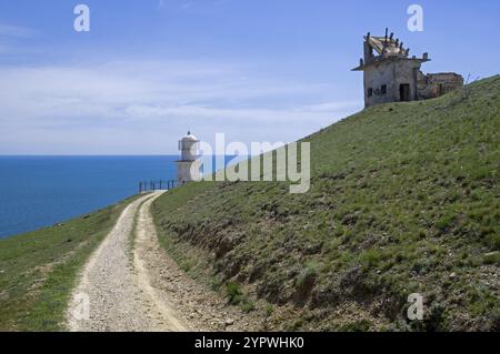 A dirt road leading along a deserted mountainside to the lighthouse. Cape Meganom, Crimea, a sunny day in April Stock Photo