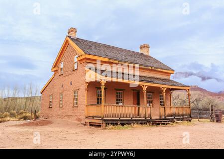 A large, old-fashioned house with a porch and a wooden railing. The house is surrounded by a dirt yard and has a rustic, country feel Stock Photo