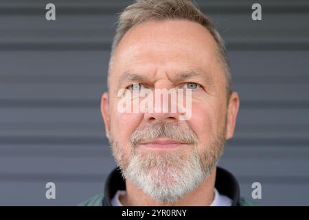 A close-up portrait of a mature man with a short gray beard and clear eyes, conveying a calm and thoughtful demeanor. Stock Photo