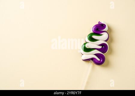 A vibrant, tree shaped spiral lollipop with purple, green, and white colors on a minimalist pastel background Stock Photo