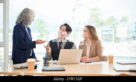 A professional, smart Asian businessman in a formal suit confidently shares his ideas and explains a project to his team during a collaborative busine Stock Photo