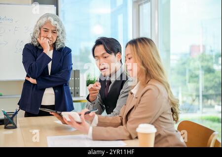 A group of diverse Asian businesspeople working together in a modern office, all focused on the discussion, sharing ideas, and planning the financial Stock Photo