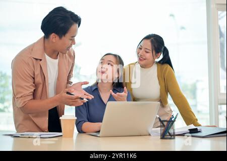 A team of smart young employees in casual clothes focused on discussing work, sharing helpful ideas, and planning upcoming projects together in a mode Stock Photo