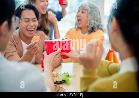 Smiling, cheerful diverse Asian employees enjoy drinks and conversations while celebrating their successful project at an office party. team building, Stock Photo