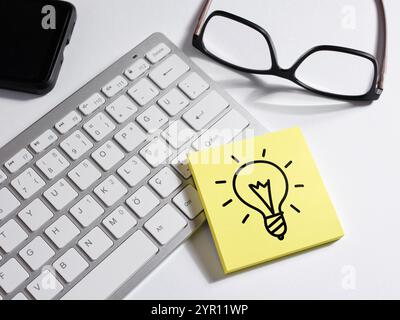 To generate and develop creative ideas. Ideas and creativity. Light bulb idea symbol on a sticky note paper. Stock Photo