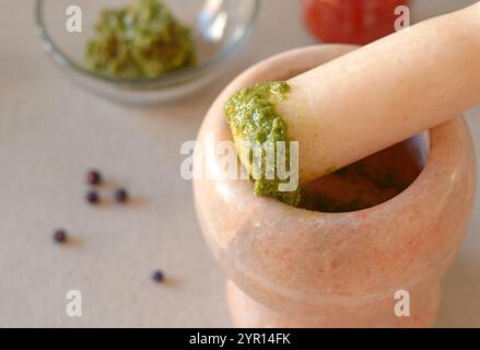 Marble mortar with pesto sauce on kitchen table. Top view. Cooking, spices and healthy eating. Traditional dishes of Italy.  Stock Photo