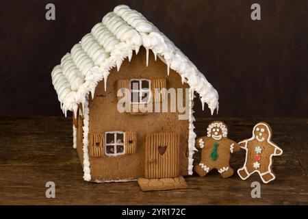 Gingerbread cookie house on wooden shelf on a dark background Stock Photo