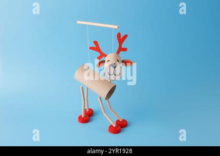 DIY reindeer puppet made from cardboard tubes, red bottle caps, paper details. on a blue background. Christmas craft and holiday decoration concept. t Stock Photo