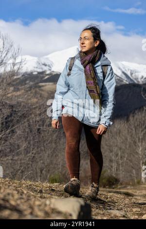 Middle aged spanish tourist woman walking on the Pyrenees mountain at winter time in a sunny day Stock Photo