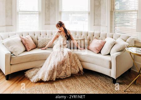 Young bride sitting indoors on white circular couch Stock Photo