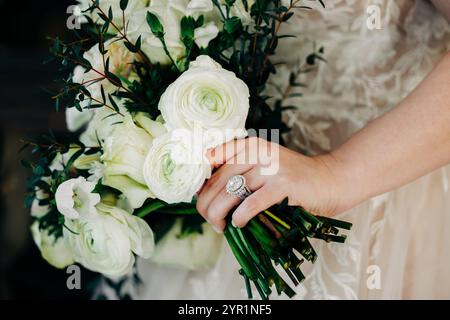 Close up of bride holding white rose flower bouquet Stock Photo