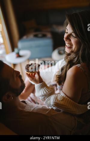 Smiling girl feeds a man with a donut closeup. Stock Photo