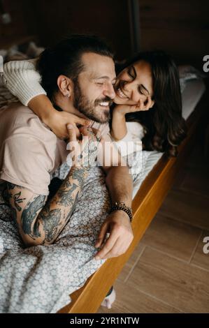 A happy young couple relaxing in bed together at home closeup.. Stock Photo