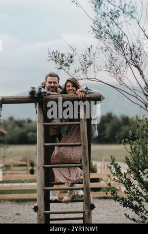 A couple standing on a large wooden swing high in the mountains. Stock Photo