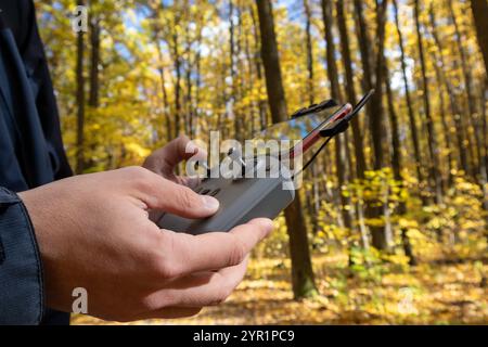 Kharkiv, Ukraine - October 15, 2021: Dji Mini (dji air) drone remote control in hands with connected phone. Operating drone close-up in autumn golden Stock Photo