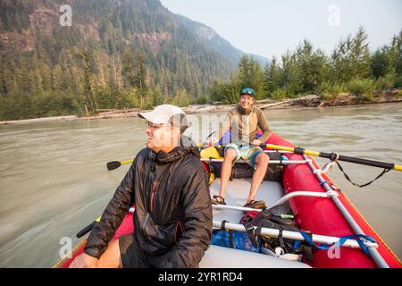 Two men laugh together during a guys weekend trip on the river Stock Photo