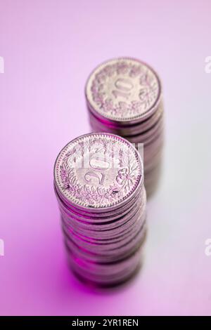 A stack of 20 Rappen and 10 Rappen Swiss Franc currency coins. Top view, isolated on white and pink, close up shot, no people. Stock Photo