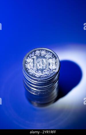 A stack of 10 Rappen Swiss Franc currency coins. Top view, isolated on blue, close up shot, no people Stock Photo